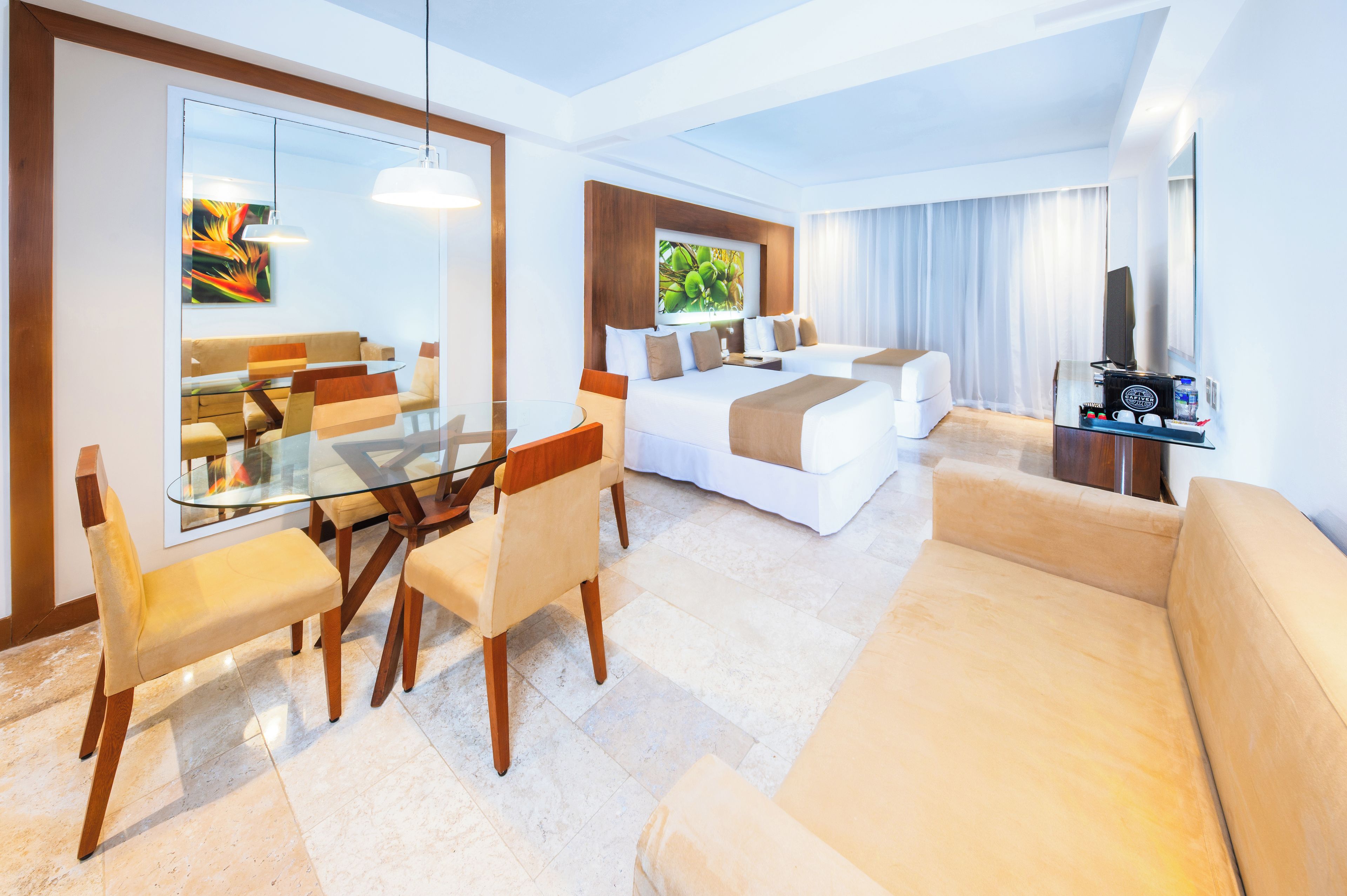 Habitación de hotel moderna con zona de comedor, sofá, cama y televisión.