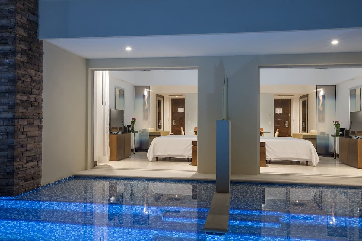 A modern hotel room with a large bed, a desk, and a bathroom.