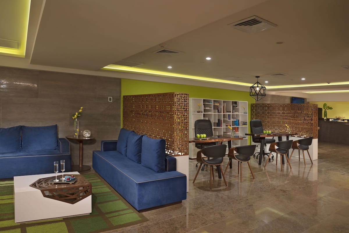 A modern living area with a blue sofa, a coffee table, a dining table with chairs, and a decorative partition.