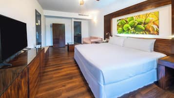 A hotel room with a large bed, a television, a desk, and a painting on the wall.