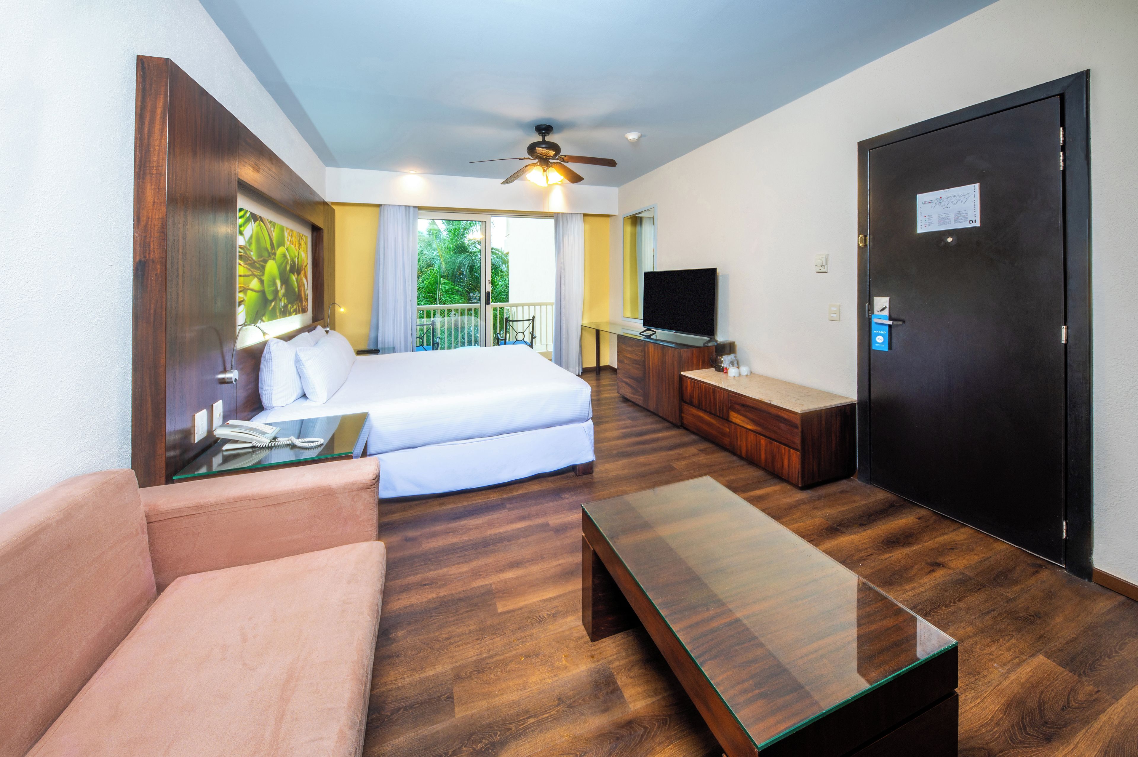 Una camera d'albergo con un letto, un divano, una televisione, una scrivania e una porta.