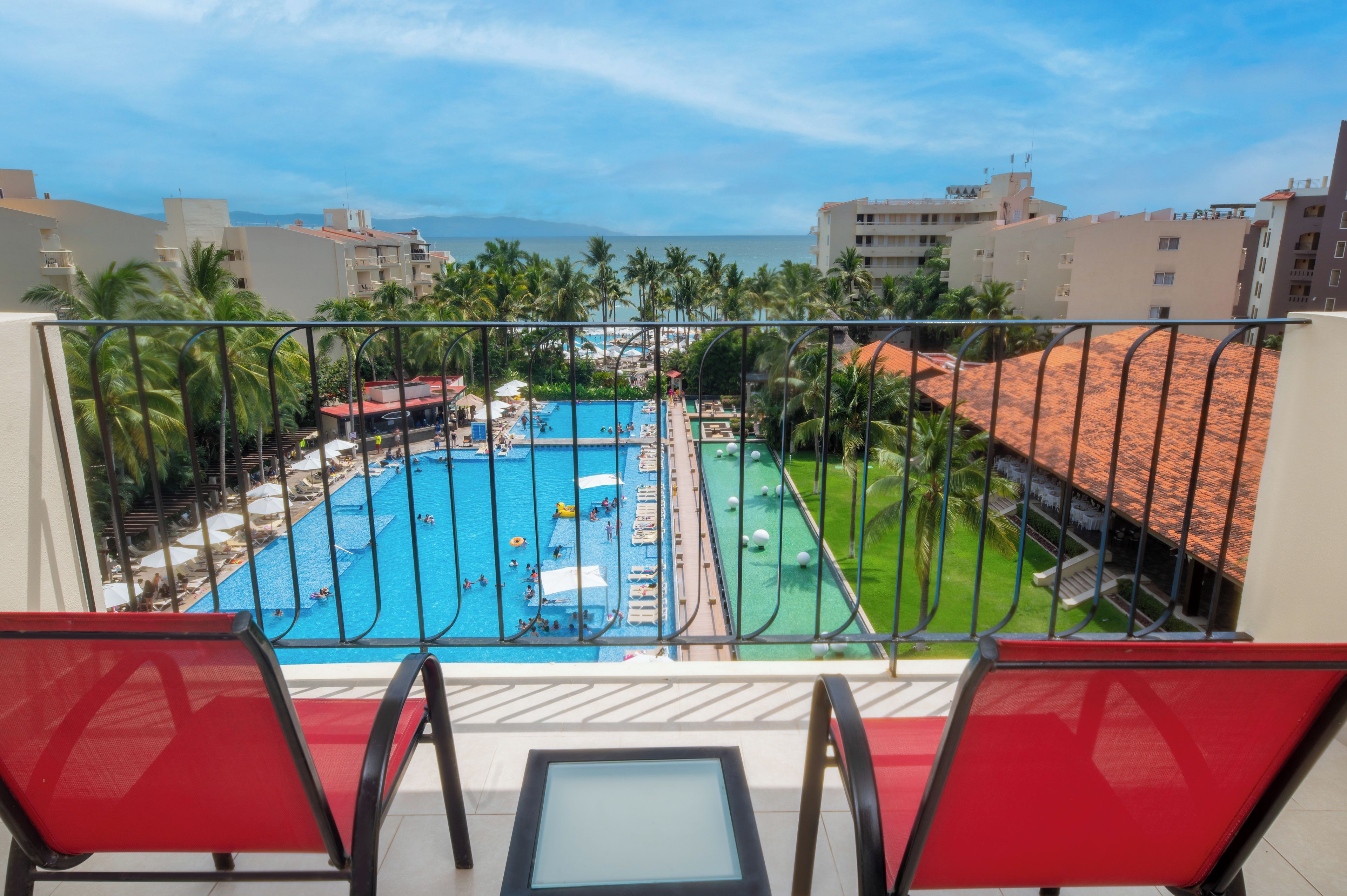 A pool area with multiple swimming pools, lounge chairs, and palm trees.