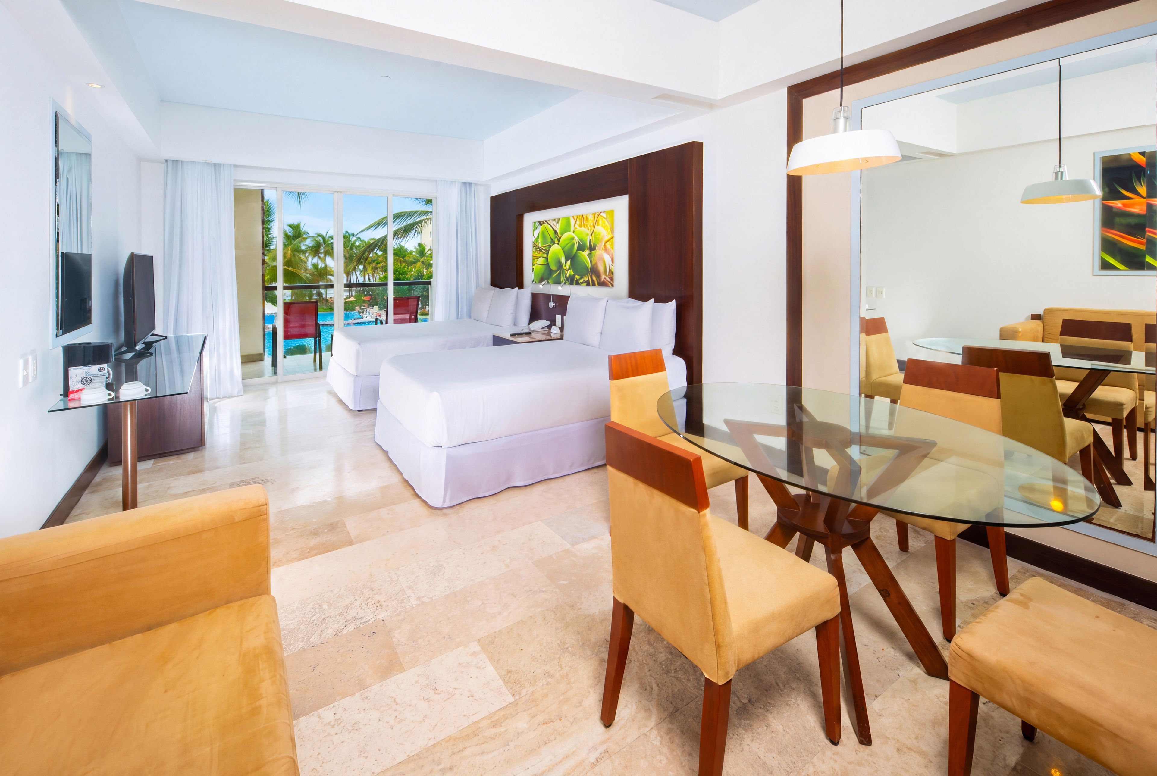 A hotel room with a bed, a desk, a dining area, and a view of a pool.