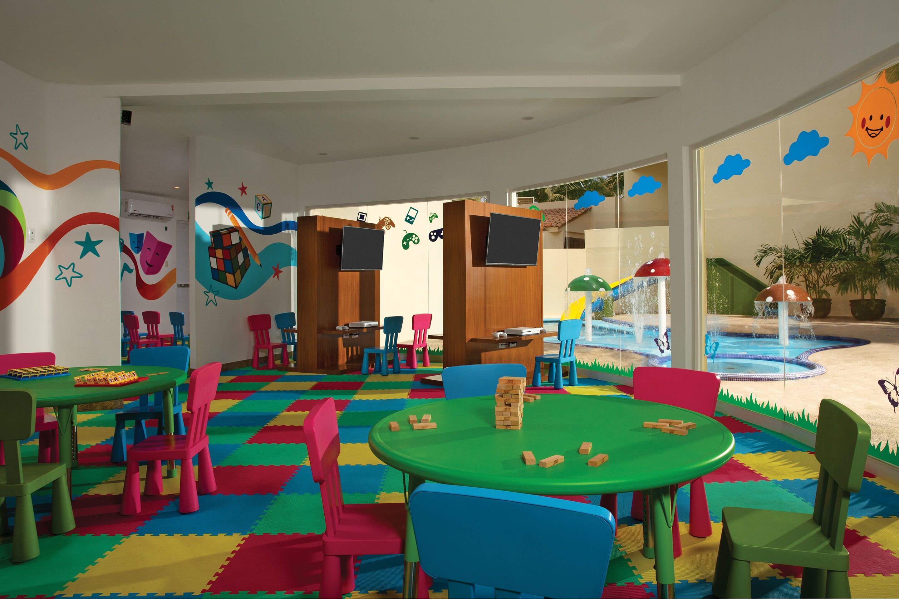 Zona de juegos infantiles con mobiliario colorido y una piscina.