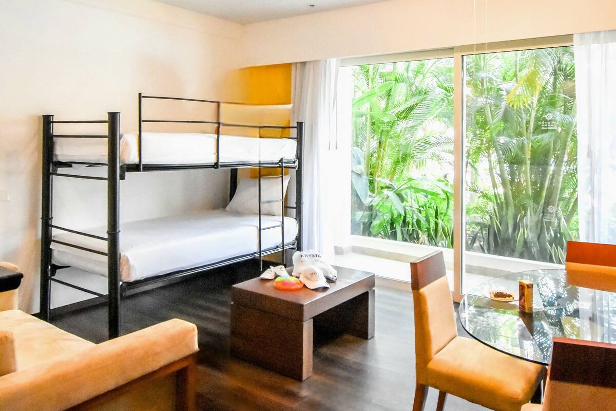 A room with bunk beds, a glass table, and a ceiling fan.