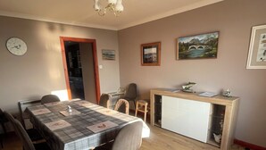 Un coin repas avec une table en bois, des chaises, une horloge et un tableau accroché au mur.
