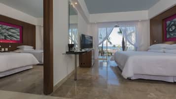 Habitación de hotel con dos camas, un escritorio con televisor y vista al océano.