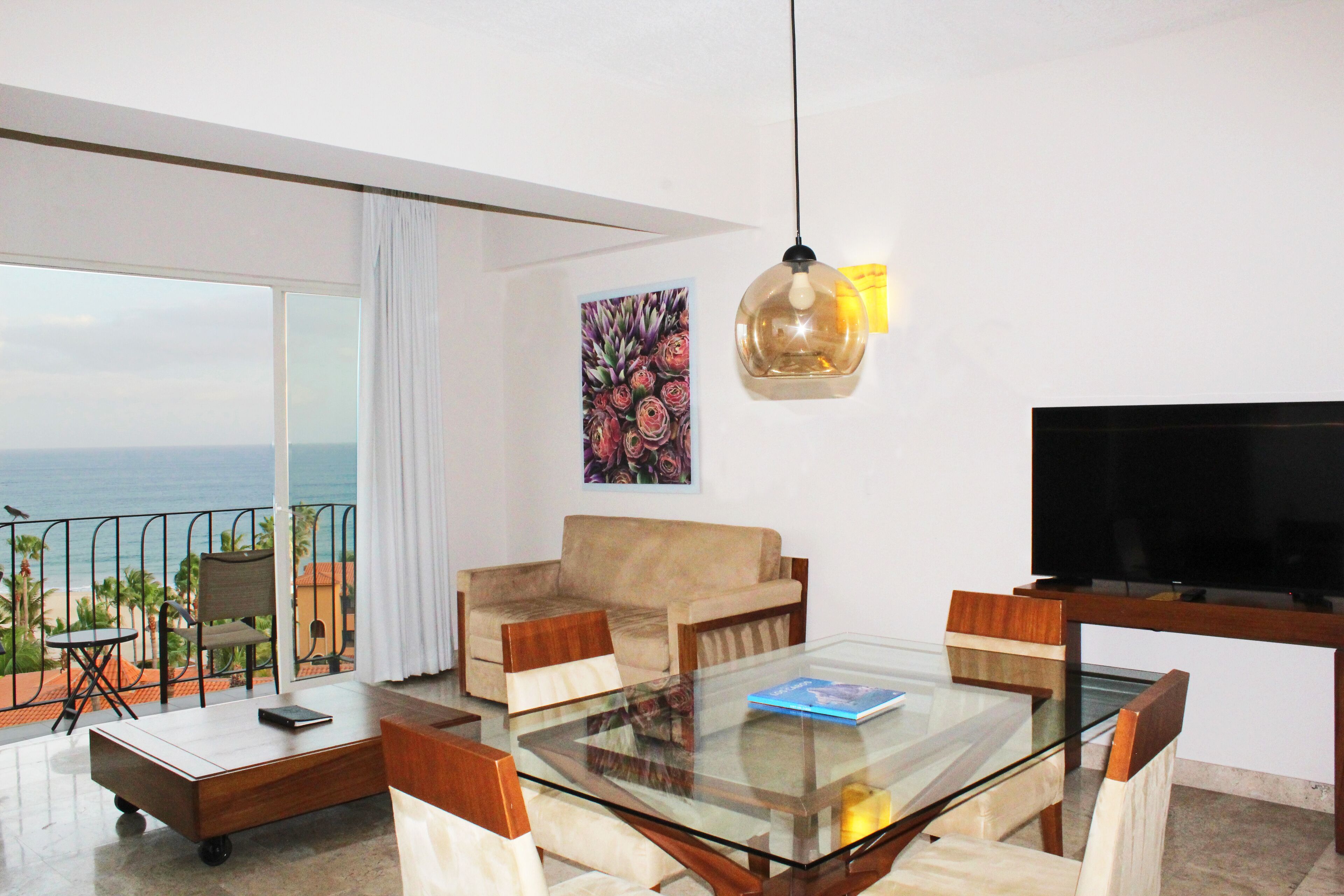 A modern living room with a glass table, a sofa, and a TV.