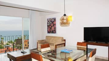 A modern living room with a glass table, a sofa, and a TV.