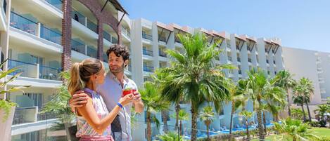 A resort with multiple balconies, a pool area, and palm trees.