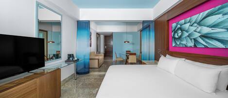 Une chambre d’hôtel moderne dotée d’un grand lit, d’un téléviseur à écran plat, d’une commode en bois et d’un coin repas avec une table et des chaises.
