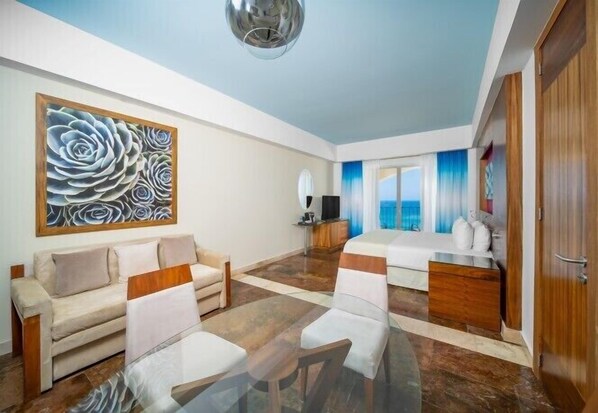 Habitación de hotel moderna con sofá, mesa de comedor y un cuadro abstracto grande en la pared.