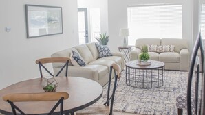A modern living room with a round dining table, two sofas, and a coffee table.