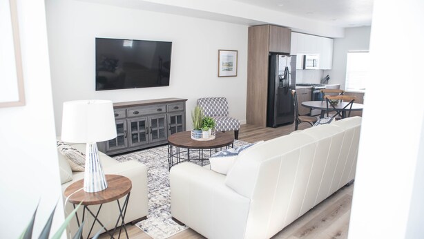 A modern living room with a white sofa, a coffee table, and a TV mounted on the wall.