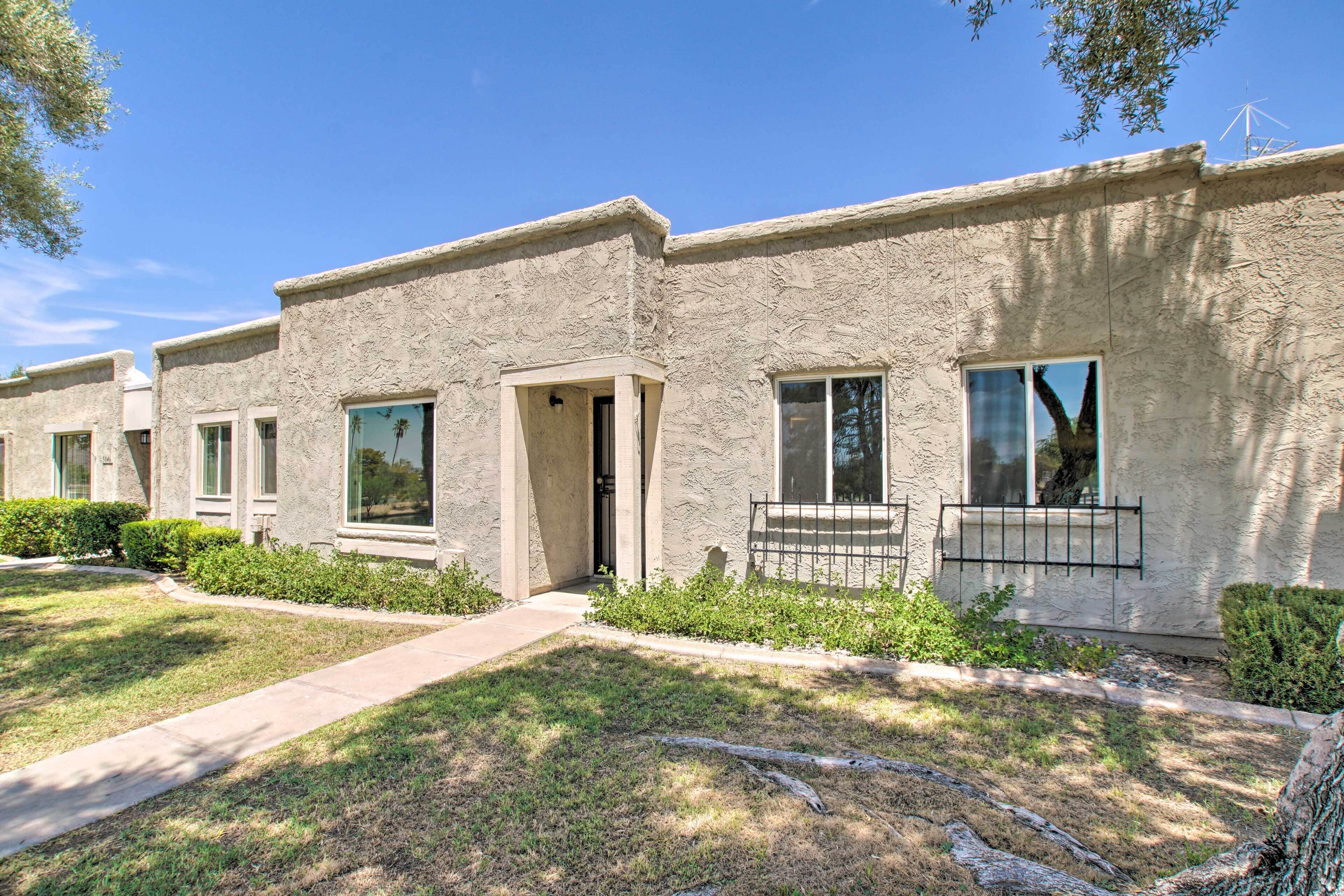A row of stucco buildings with large windows and a well-maintained lawn.