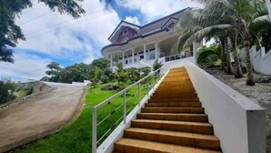 A staircase leading to a house with a porch, surrounded by greenery and palm trees. - Canoy's Mansion Apartelle in Dalaguete Cebu (Dalaguete)