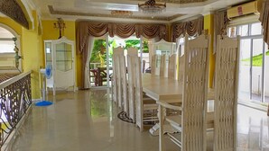 A dining area with a long table, chairs, and a chandelier. - Canoy's Mansion Apartelle in Dalaguete Cebu (Dalaguete)