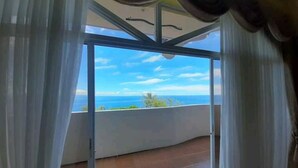 A room with a large sliding glass door leading to a balcony with a view of the sea. - Canoy's Mansion Apartelle in Dalaguete Cebu (Dalaguete)