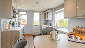 A modern kitchen with white cabinets, a built-in microwave, and a large window.
