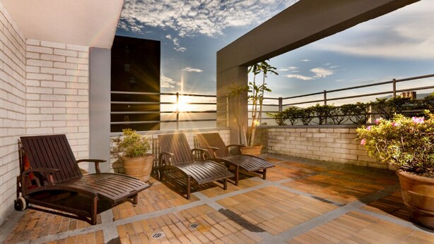 A rooftop terrace with a sunset view, a brick wall, and potted plants. - Loslan Real Estate (Medellín)