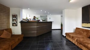 A reception area with a counter, two sofas, and a brick wall. - Loslan Real Estate (Medellín)