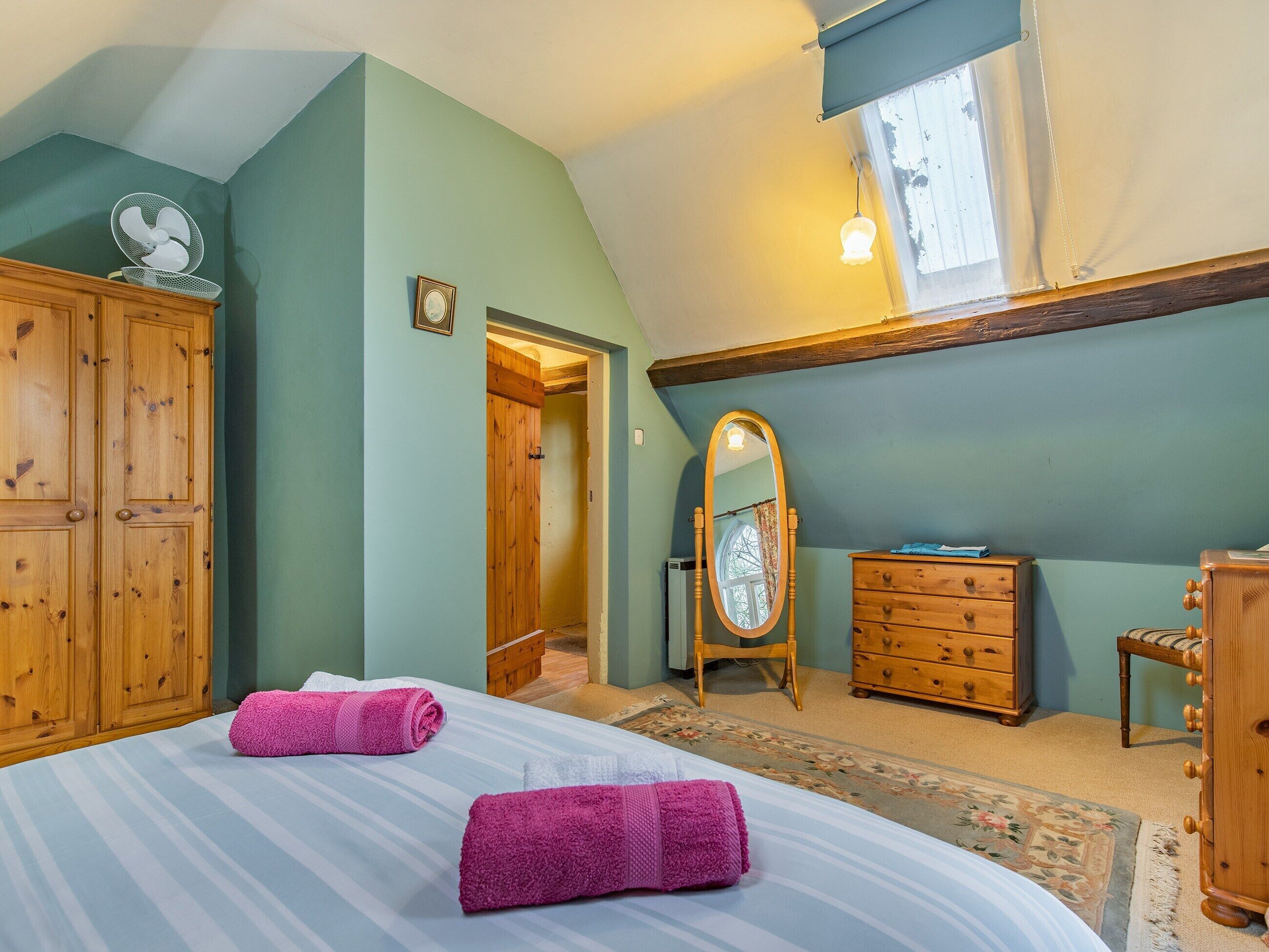 Un dormitorio con cama, armario de madera, cómoda y espejo.