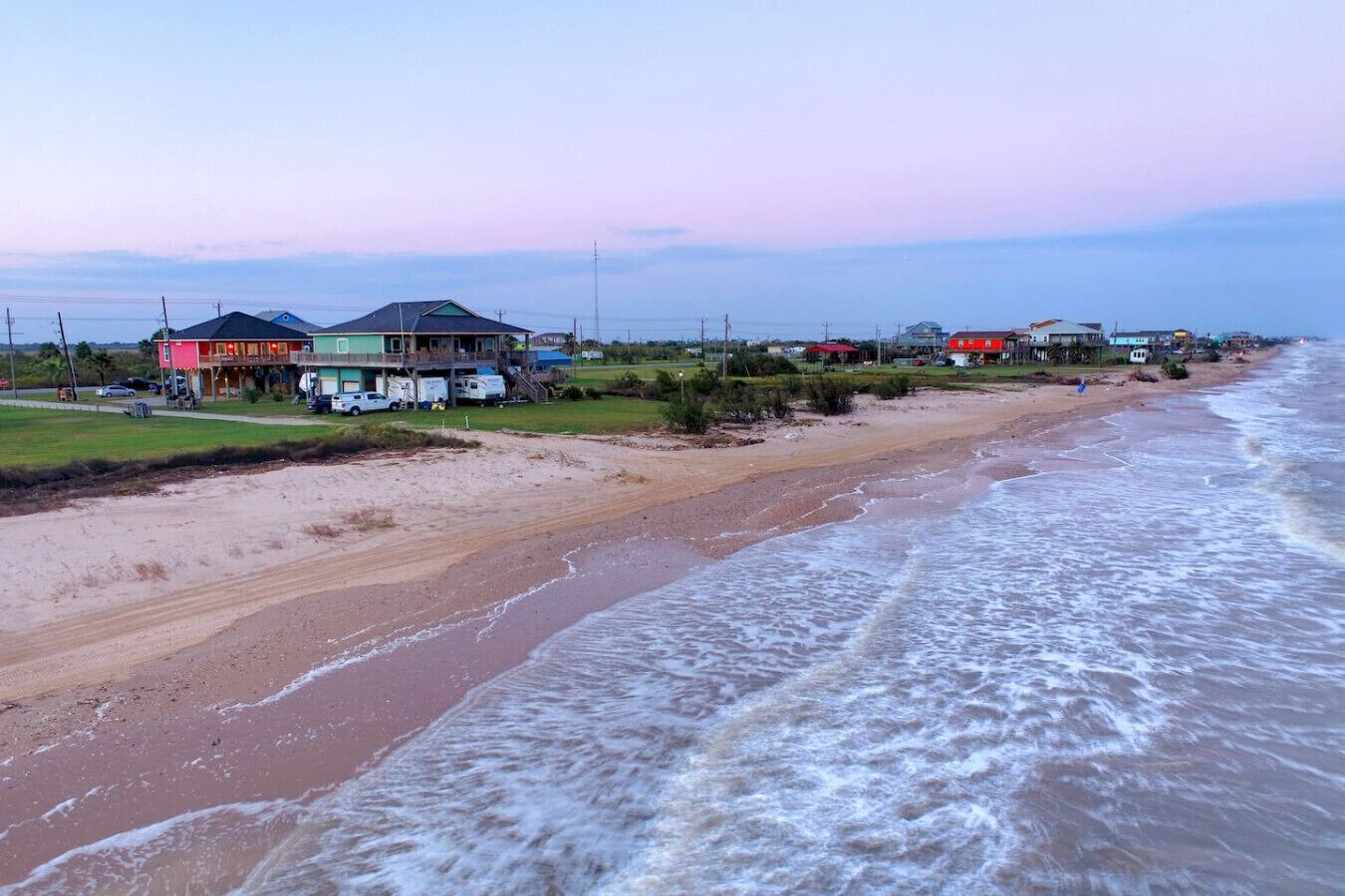 A beachfront property with a large house, a smaller building, and a beach in the background.