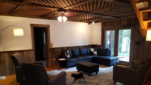 A cozy living room with a sectional sofa, two armchairs, a small round table, and a ceiling fan. - Awesome Lake House with Natural Beach, Huge Dock, and Sunset Views. Sleeps 9 (Moneta)