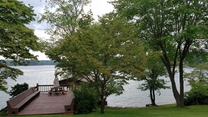 A wooden deck with benches overlooking a lake, surrounded by trees. - Awesome Lake House with Natural Beach, Huge Dock, and Sunset Views. Sleeps 9 (Moneta)