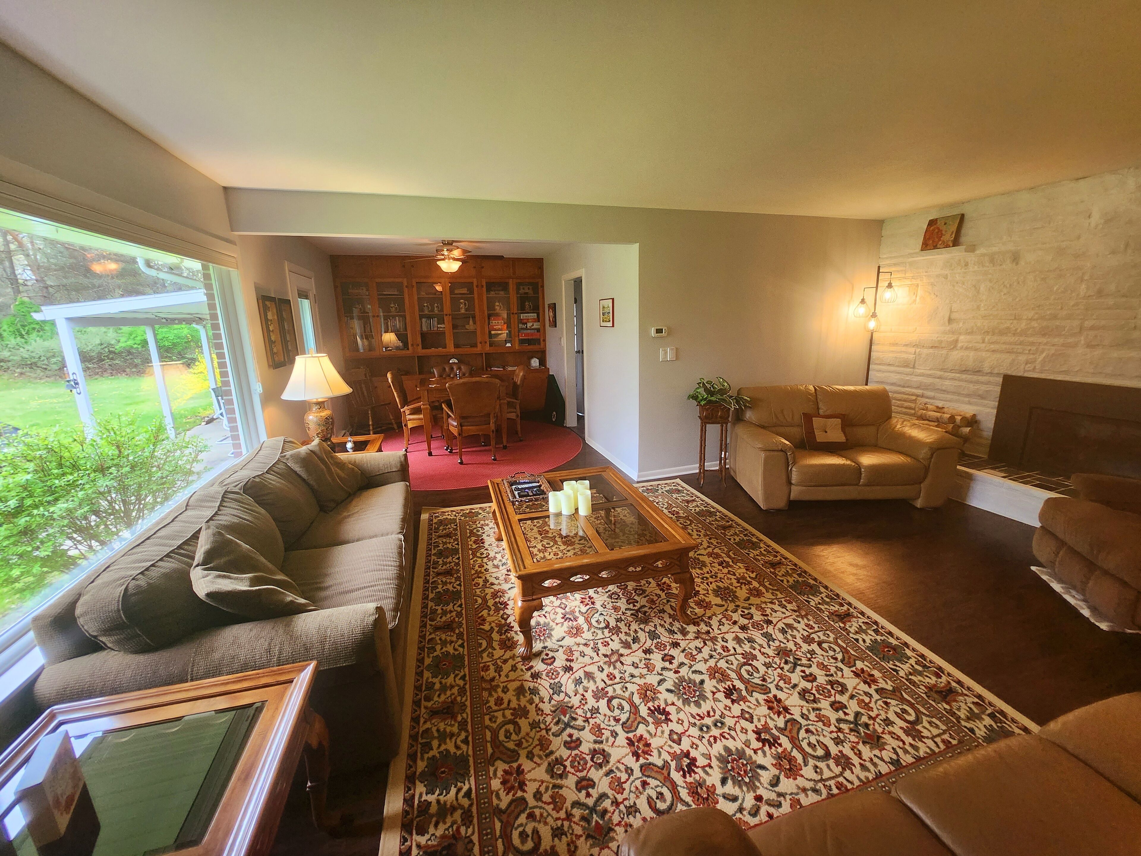 A living room with a sofa, armchairs, a coffee table, a fireplace, and a bookshelf.