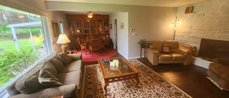 A living room with a sofa, armchairs, a coffee table, a fireplace, and a bookshelf.