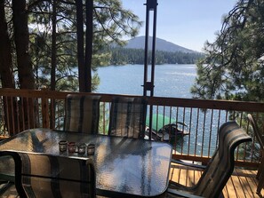 Eine Holzterrasse mit einem Glastisch und Stühlen mit Blick auf einen See.