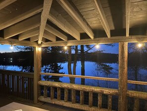 A wooden deck with a view of a lake at dusk. - Lakefront Cabin w/ Hot Tub, Views & Fireplace (Lake Harmony)