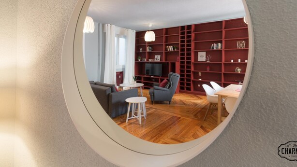 En moderne stue med en rød reol, en grå sofa og et hvidt sofabord.