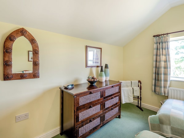 Une pièce comprenant une commode en bois, un miroir, une horloge et une fenêtre avec des rideaux.