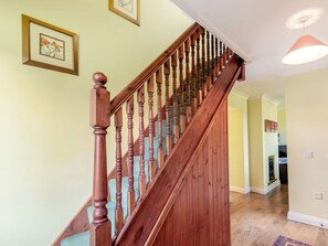 A wooden staircase with a handrail, carpeted steps, and a light fixture above.