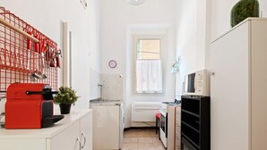 Una cocina compacta con un electrodoméstico rojo, un refrigerador blanco y un microondas.