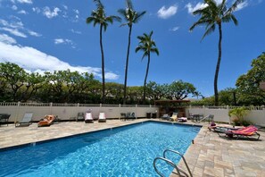A swimming pool with lounge chairs and palm trees.