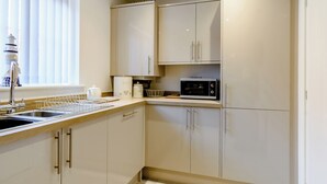 Une cuisine moderne avec des meubles blancs, un four à micro-ondes et un évier.