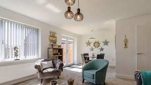 Un salon chaleureux avec une cheminée, un coin repas et une vue sur l’extérieur.