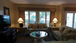 A living room with a sofa, a coffee table, a TV, and two lamps.