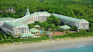 A large resort with multiple buildings, a beach, and a forested area.
