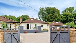 Un lotissement résidentiel fermé, avec une allée pavée menant à une maison dotée d’un toit en tuiles et d’une cheminée en briques.