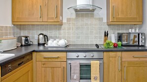Une cuisine moderne avec des meubles en bois, un lave-vaisselle Bosch, un four à micro-ondes et une hotte aspirante.
