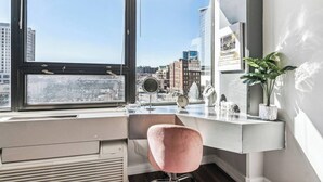 A modern workspace with a large window, a pink chair, and a city view.