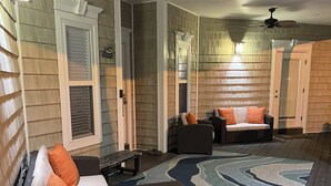 A covered outdoor seating area with wicker furniture, a patterned rug, and ceiling fans. - Custom Home on LakeFront in Ocean Lakes (Myrtle Beach)