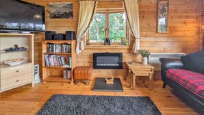 A cozy cabin interior with wooden walls, a television, a bookshelf, a coffee table, and a couch. - 2 bedroom accommodation in Black Isle (Black Isle)