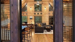 Interior acogedor de una cabaña de troncos con comedor, sofá y ventilador de techo.