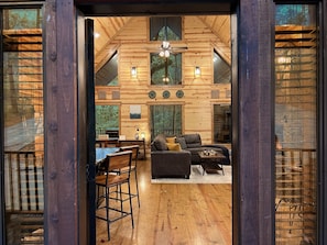 L’intérieur d’un chalet confortable, avec une salle à manger, un canapé et un ventilateur de plafond.