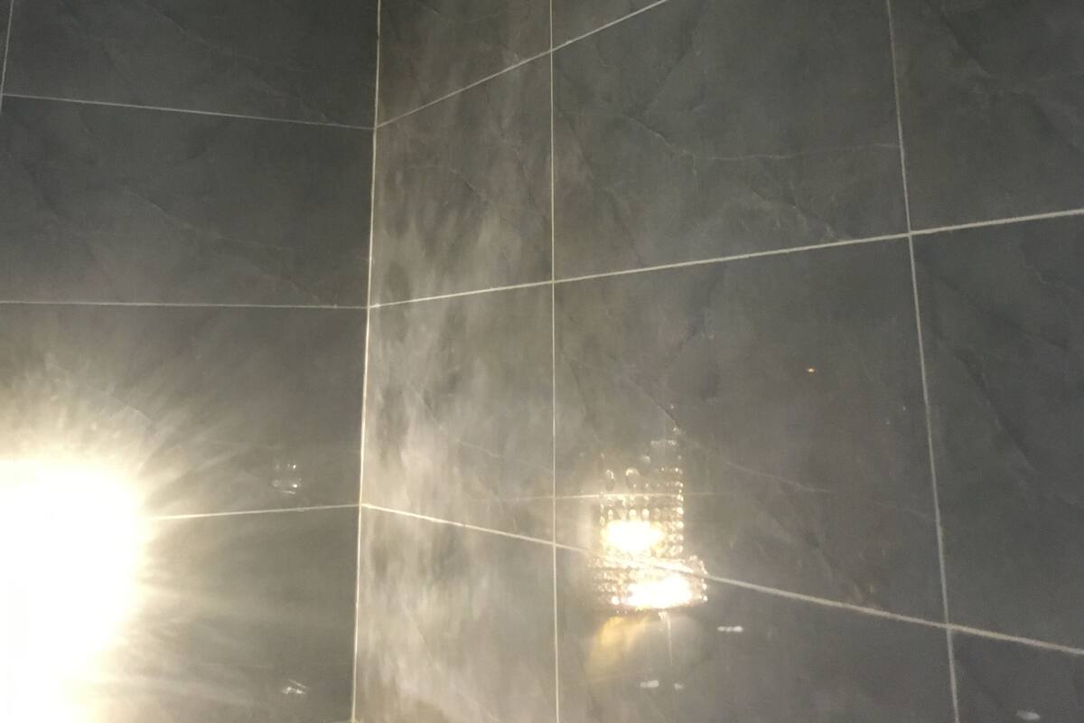 Una habitación con paredes de baldosas grises oscuras y un techo con desperfectos.